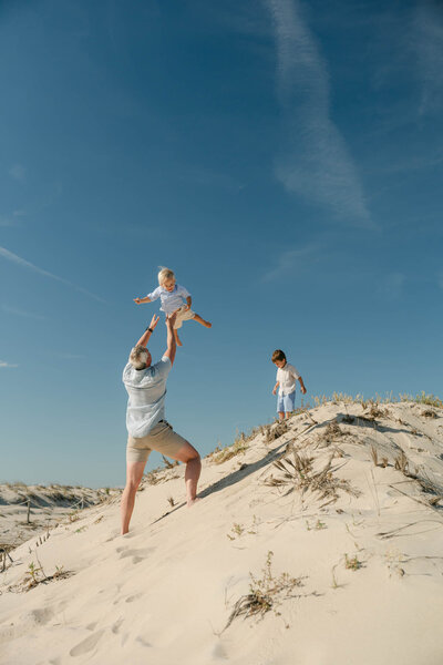 Father throws son into the air at the beach in Delaware