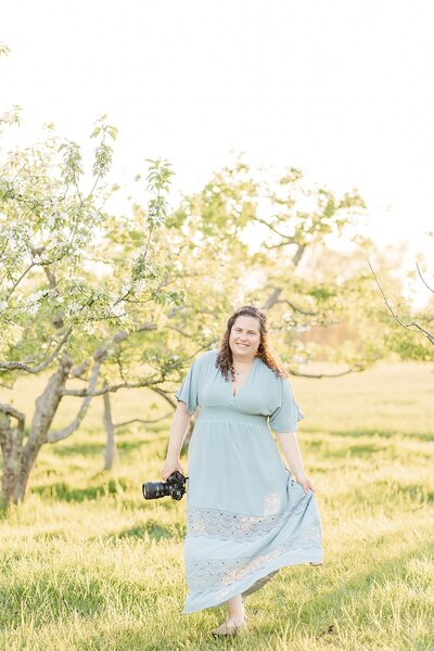 Sara Sniderman walks through orchard with camera in Natick Massachuestts