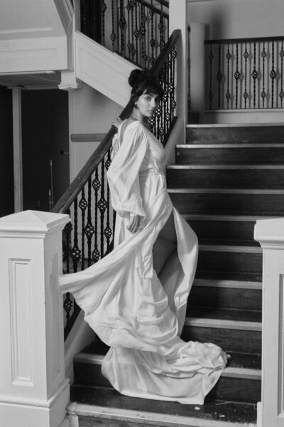 Long-sleeved silk wedding dress with deep v back worn by bride in country estate