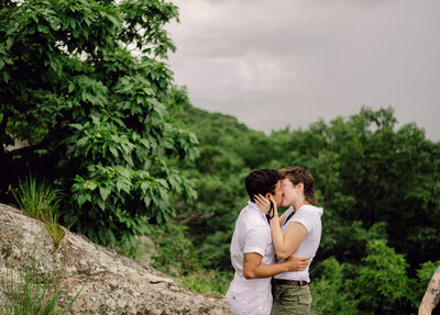 Bride and groom standing hand in hand with a mountain lake behind them during their intimate Virginia elopement, photographed in natural light and soft tones.

