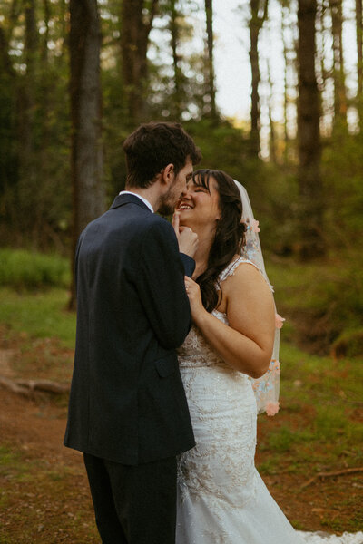 bride and groom standing in forest about to kiss