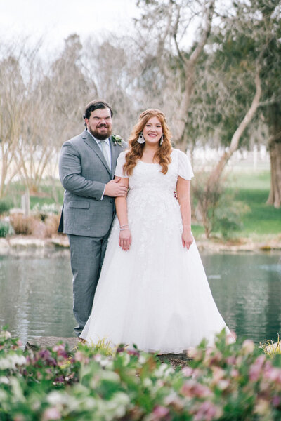 bride and groom hold hands at pond at marblegate farm wedding venue in friendsville tennessee