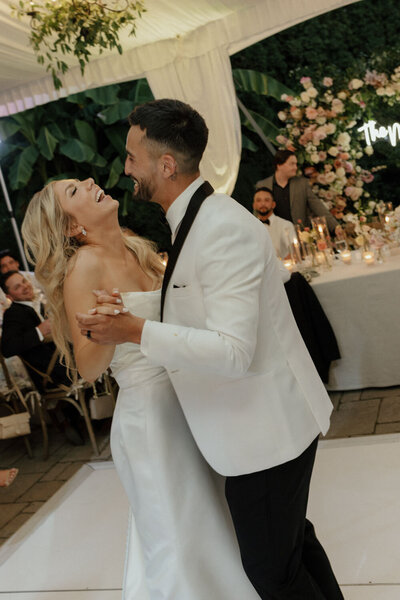 Bride and groom dancing under a floral backdrop