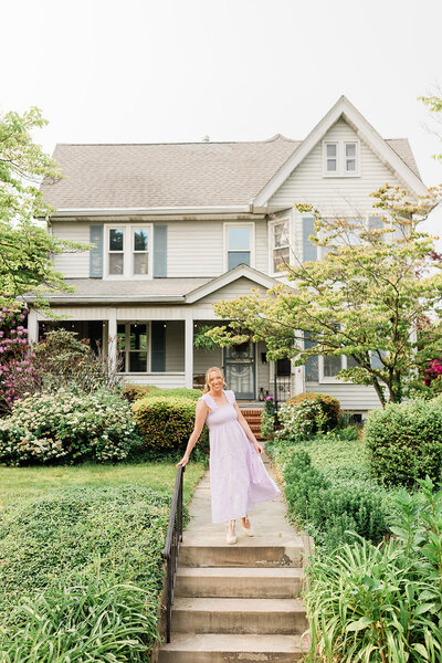 A female homeowner stands in front of her Victorian house.