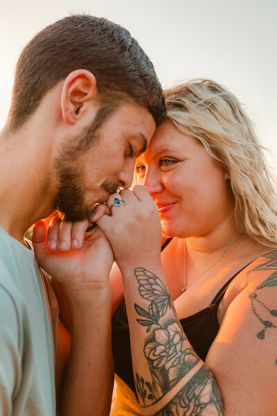 couple leaning in forehead to forehead at Garden of the Gods in Southern Illinois as he makes a pinky promise and kisses her ring finger during their intimate engagement session.