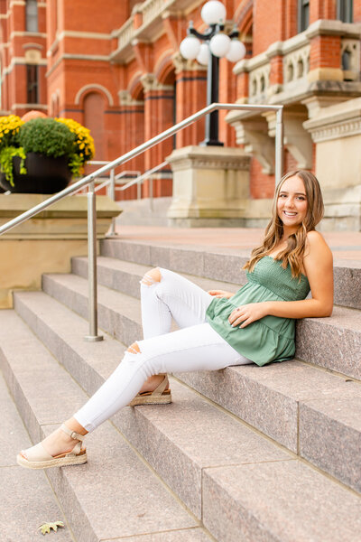 Senior girl sitting in front of city building