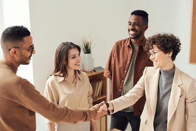 Group of professionals smiling and shaking hands in an office setting, representing S Corporation tax return services starting at $349 with one state return included