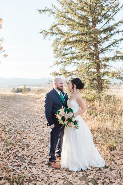 groom holding his bride around the waist as the bride smiles  at him