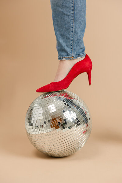 a red high heel steps on a disco ball
