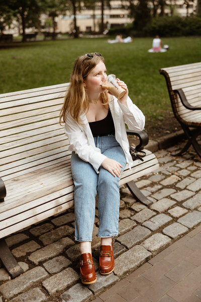 Photo of Lydon sitting on a bench drinking coffee