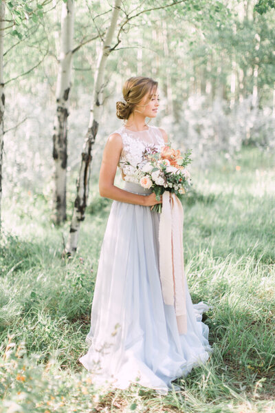 bride posing in the forest for a wedding portrait wearing a light blue gown