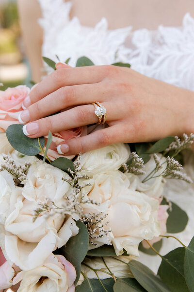 Close up of a hand on a pale floral boutique showing her engagement ring and wedding band.