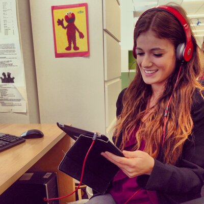 Madison using a tablet at her desk at Sesame Workshop during her early career in EdTech, with an Elmo poster in the background.