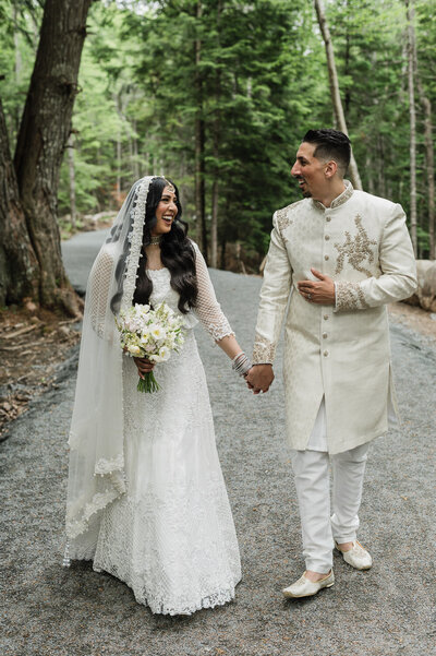 Bride and groom smiling at each other while holding hands.