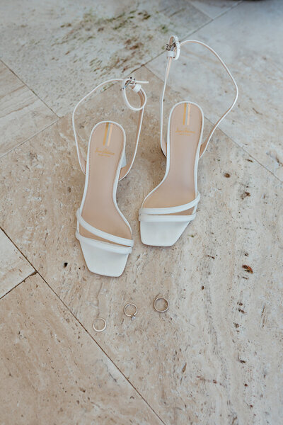Minimal flatlay of Bride's heels and wedding bands. 
