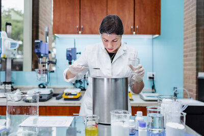 A woman in a lab coat working on the production of cosmetic products.