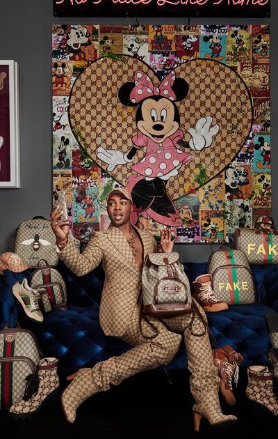 Bold portrait of Todrick Hall in a Gucci floral suit, seated confidently against a patterned backdrop, captured by Ylva Erevall.
