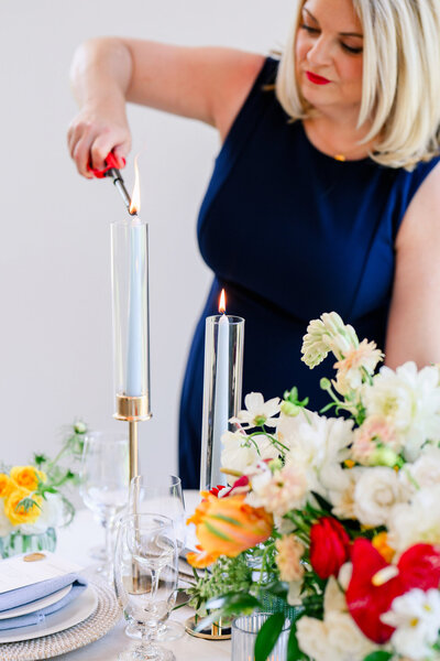 Austin wedding planner lighting candles at a modern wedding reception, adding finishing touches to a thoughtfully styled table setting.