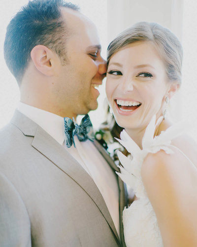 Groom + Bride sitting back to back in museum turning smiling at one another