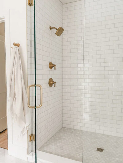 The walk-in shower features simple but elegant brass fixtures including a showerhead and handheld shower