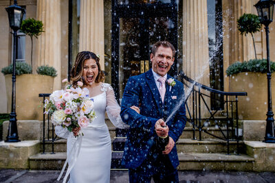 wedding couple doing a champagne shower towards the camera