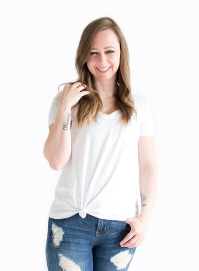 Female in white shirt and blue jeans smiling at the camera