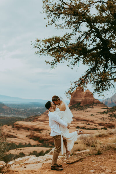 man and woman kiss at merry go round rock in sedona for engagement photos