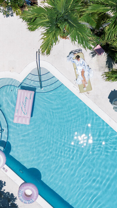 Drone shot of a bride laying in the swimming pool at the Colony hotel Captured by Sunny Lee Photo,