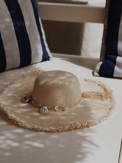 Straw beach tote, earrings and bikini next to luxury pool