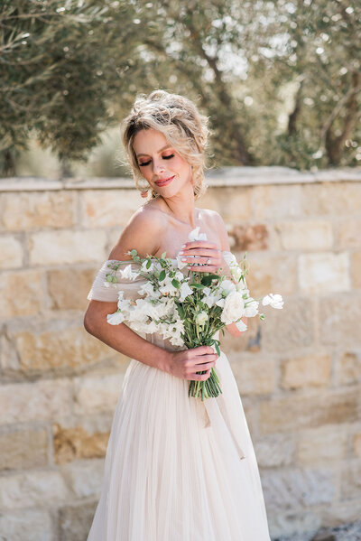 A bride holds a bouquet on her sunny desintation wedding day