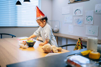 ダイニングテーブルでフルーツに手を伸ばす女の子