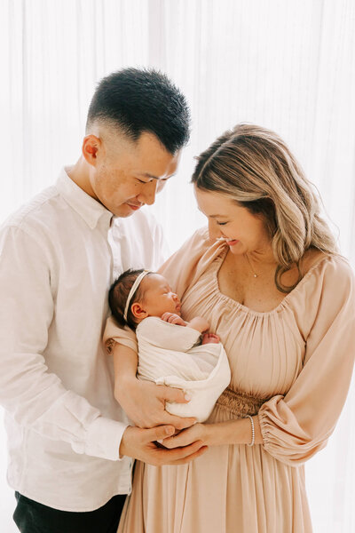 family portrait of parents holding newborn baby
