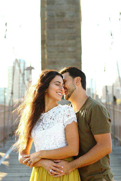 husband and wife posing for photos on the brooklyn bridge