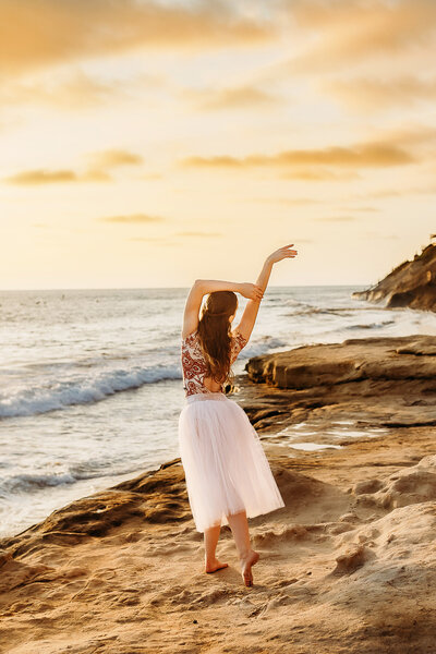 High school senior dancer dancing at the sea in the sunset.