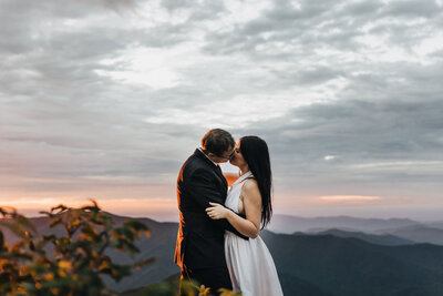Bride and groom kissing in the  Asheville NC mountains during sunrise