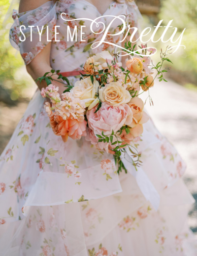 Close-up of a bride holding her bouquet, wearing a wedding dress with floral embroidery details.