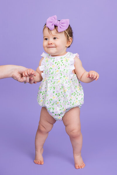 Portrait of a baby in a purple bow on a purple backdrop