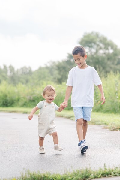 a boy walking while holding hands with his younger brother