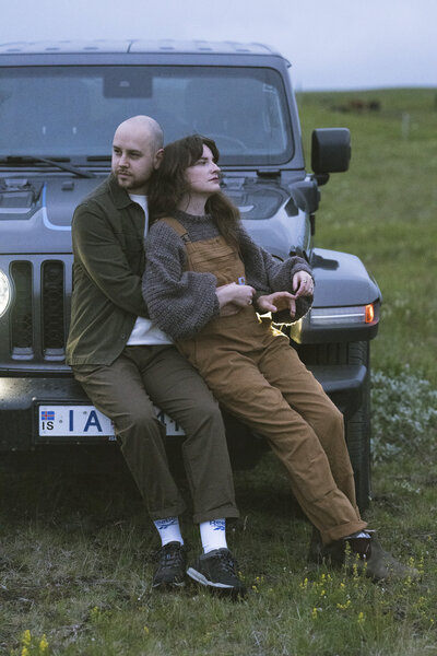 couple holding each other leaning against a car