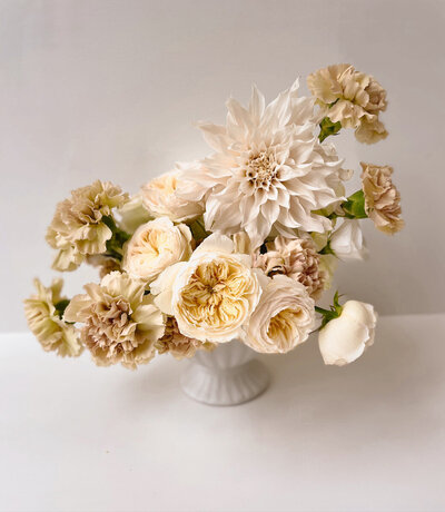 Bruiloft tafelstuk met bloemen in beige kleuren. Dahlia cafe au lait, anjer en rozen
