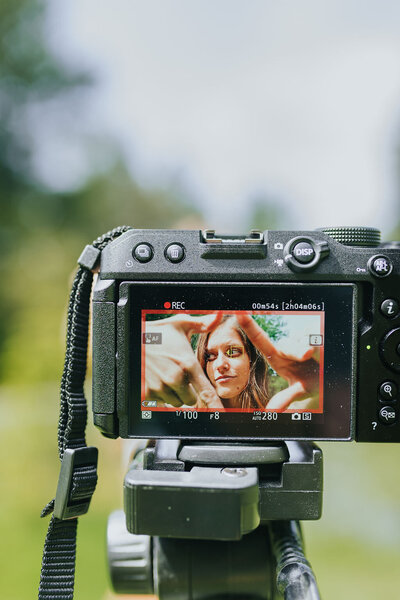 Camera screen shows woman creating square "frames" with her hands in front of camera.