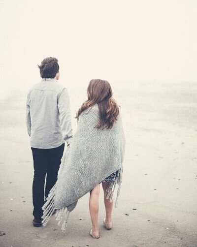 A couple join hands as they walk together on a foggy beach. They are facing away from the camera, and feel distant while working on their affair recovery in Florida. This could symbolize the emotional distance that can result from an affair. Contact us to begin our affair recovery program in Florida, and receive support in recovering from infidelity.