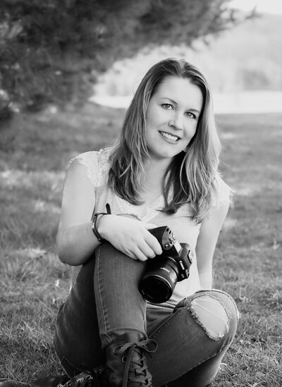Image of Baltimore wedding photographer, Kimberly Dean, posing in the grass with her camera.
