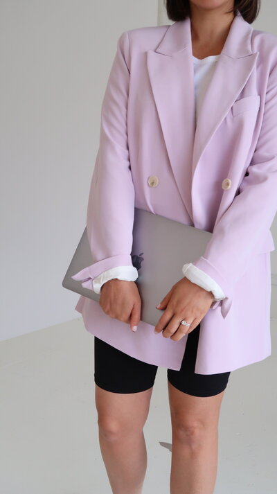 lady in pink jacket holding a mac laptop with both hands