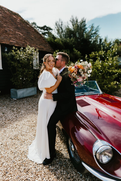 A BRIDE AND GROOM KISS IN THE BARN AT SILCHESTER FARM IN HAMPSHIRE
