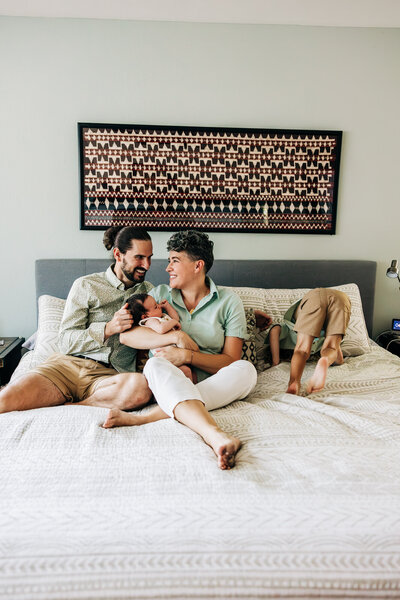 Fun family of four bouncing on the bed with a toddler and newborn in st. petersburg