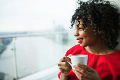 Woman holding a glass of coffee while watching the view