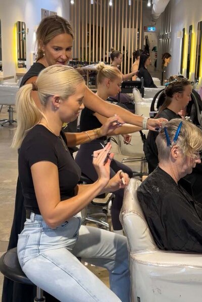Katy Reeve Educating hairdressing students practicing cutting techniques on clients in a modern salon with sleek interiors.
