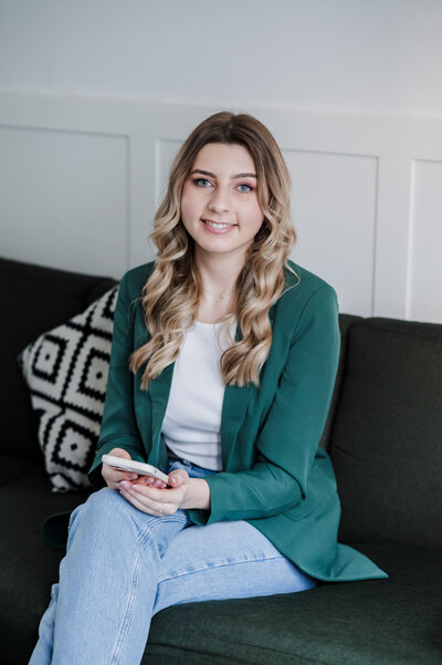 Wedding Content creator sat on a sofa holding a phone and smiling towards the camera