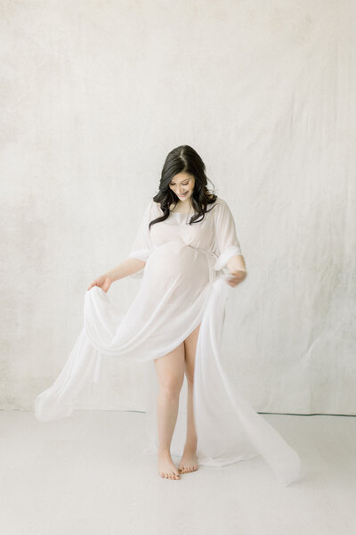 A maternity portrait of an expecting mother dancing around in a Dallas photography studio.